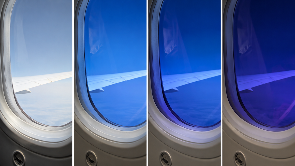 Four airplane windows show the view outside gradually darkening, from bright daylight to a deep blue tint, demonstrating the effect of adjusting the window dimming shades.