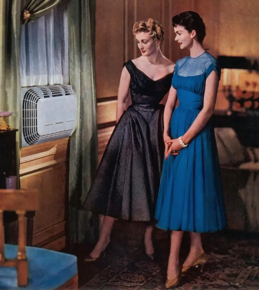 Two women in elegant 1950s dresses stand by a window looking at a vintage air conditioner. The room is warmly lit and decorated with classic furniture and curtains.