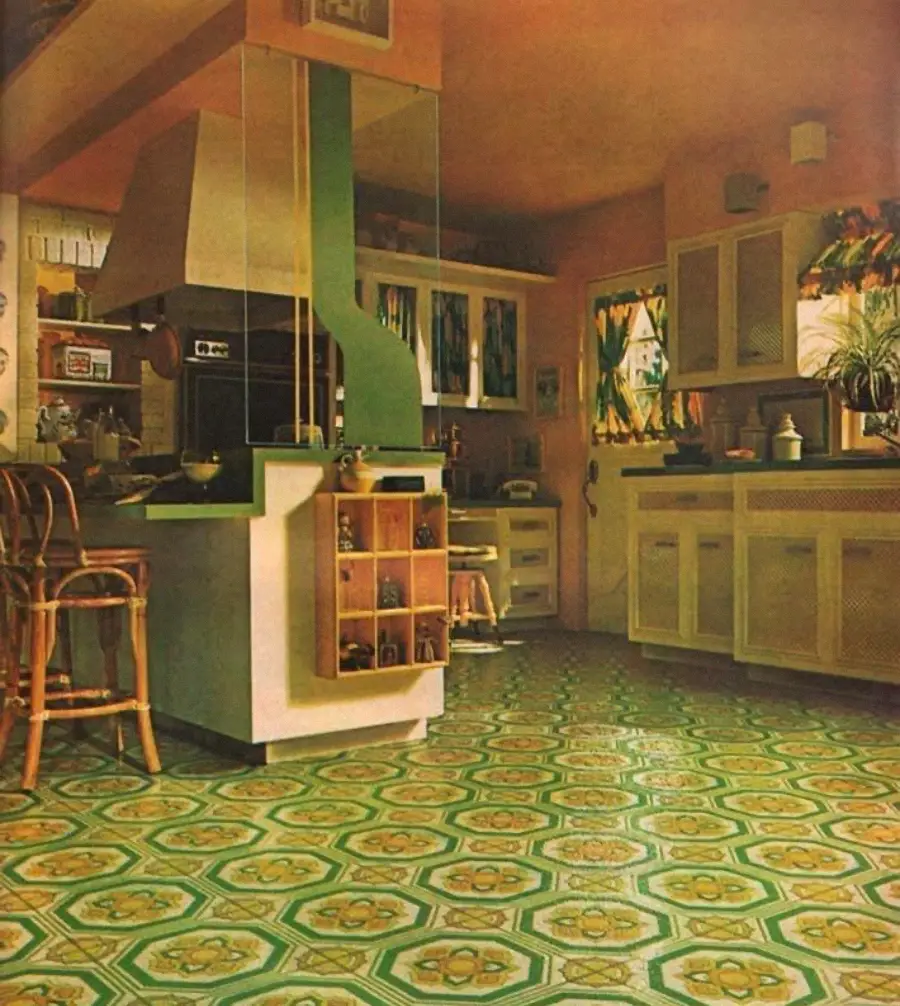 1970s kitchen with green patterned floor, rattan chairs, green range hood, yellow curtains, light cabinets, and potted plants; sunlight filters through windows, creating a warm retro atmosphere.