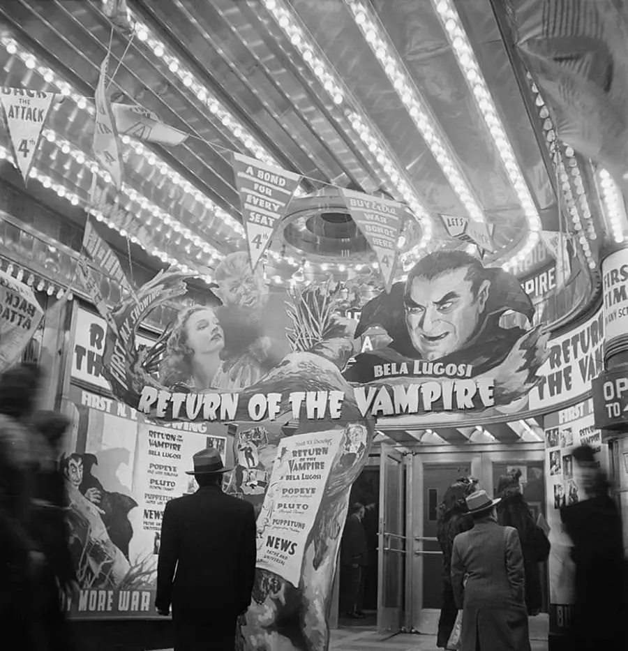 Black-and-white photo of people in hats entering a theater with bright lights and posters for the film “Return of the Vampire” starring Bela Lugosi, featuring dramatic artwork and promotional banners.