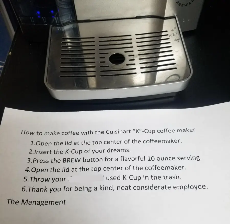 A printed instruction sheet for making coffee with a Cuisinart K-Cup maker sits next to the coffee machine. The instructions list six steps for brewing and cleaning up a used K-Cup.