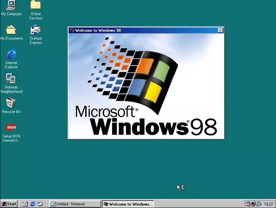 A computer desktop running Windows 98 shows a large “Welcome to Windows 98” popup with the Windows logo. Icons for My Computer, Network Neighborhood, Outlook Express, and The Internet are on the left. Taskbar is at the bottom.