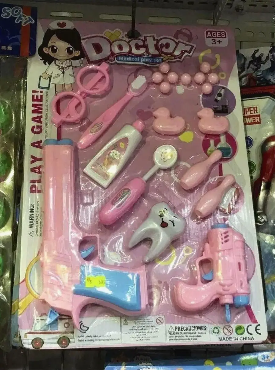 Children’s pink doctor playset on display, including toy syringes, stethoscope, tooth, dental tools, toothbrush, toothpaste, and medical bottles. Packaging is pink, with cartoon doctor art. For ages 3 and up.
