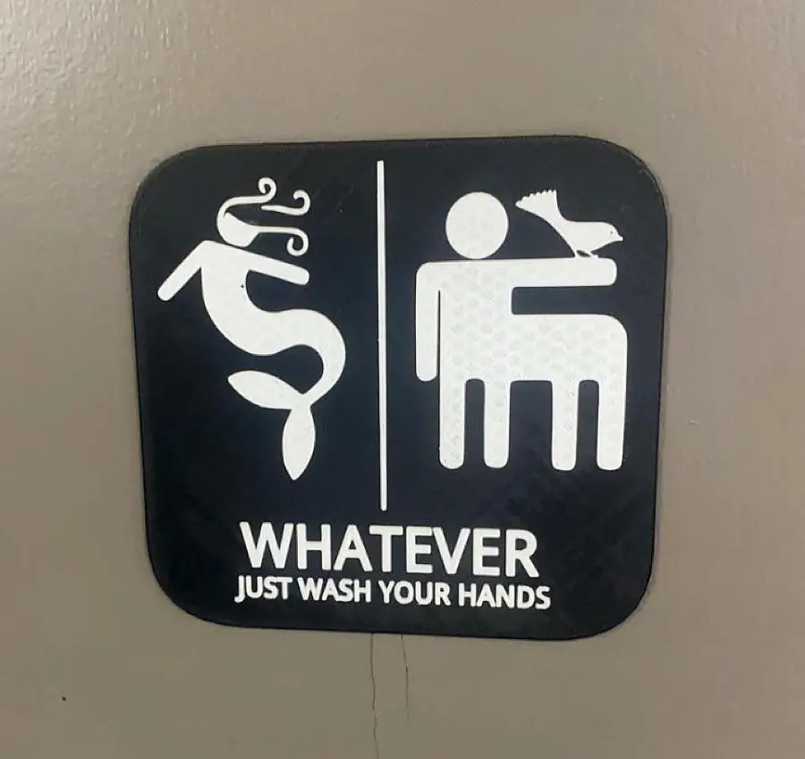 A sign with a mermaid on one side and a human with a bird on their arm on the other. Text below reads, “WHATEVER. JUST WASH YOUR HANDS.”