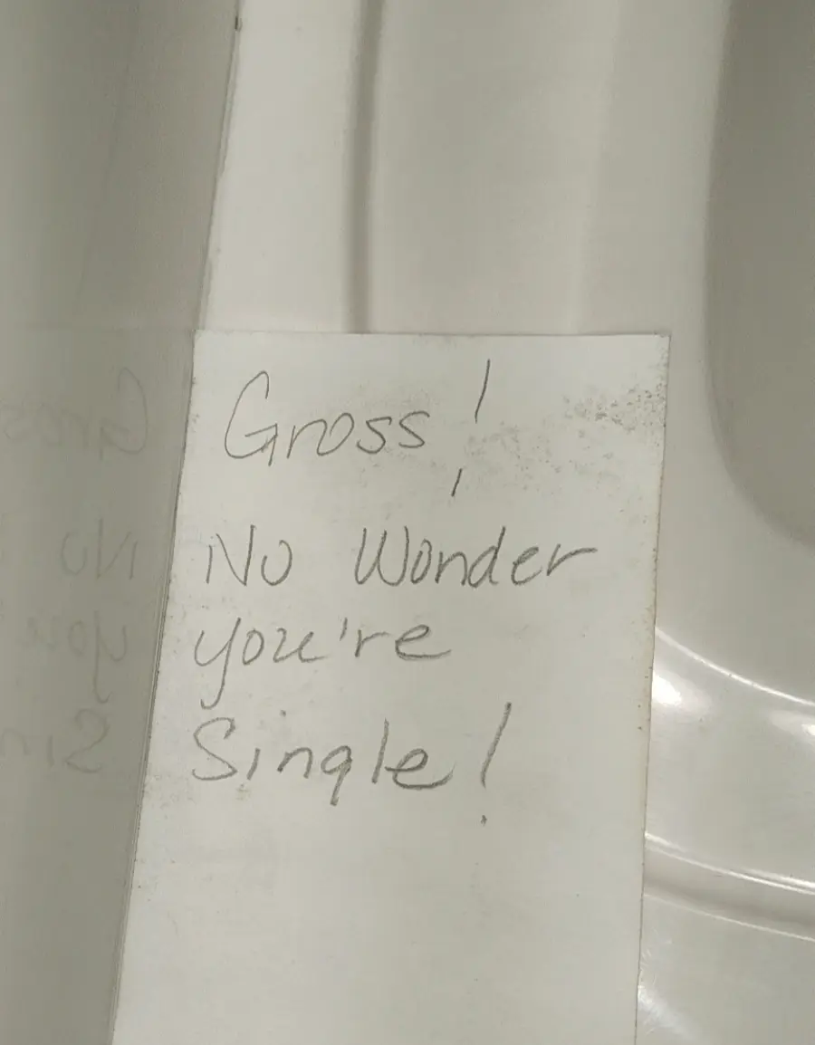 A handwritten note says, “Gross! No wonder you’re single!” The note is taped to a shiny white surface, possibly in a bathroom.
