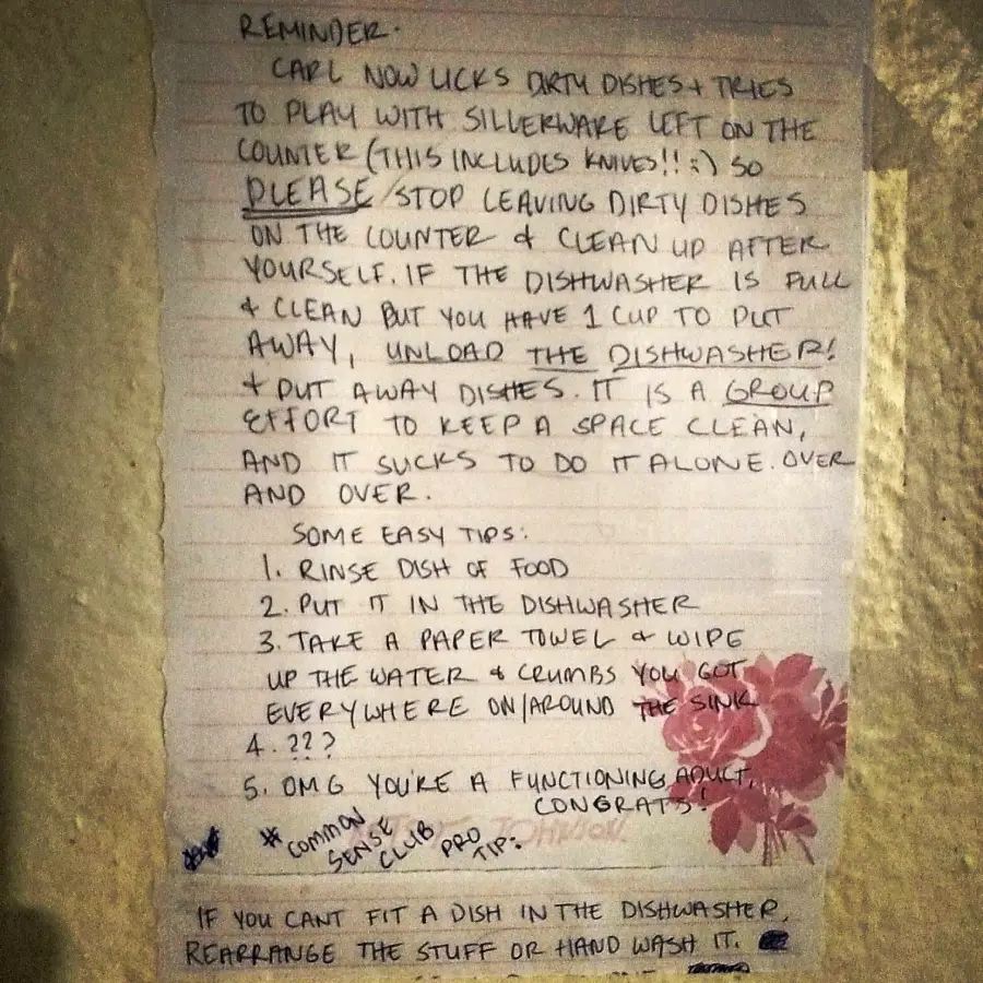 A handwritten note on lined paper taped to a wall outlines rules about cleaning dishes, emphasizing teamwork, and lists easy steps for using the dishwasher. There is a flower illustration near the bottom.