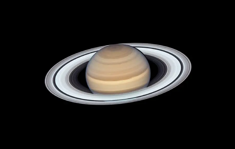 Saturn with its distinct rings, viewed against a black background. The planet shows subtle brown and yellow bands, while the rings appear bright with some shadowing.