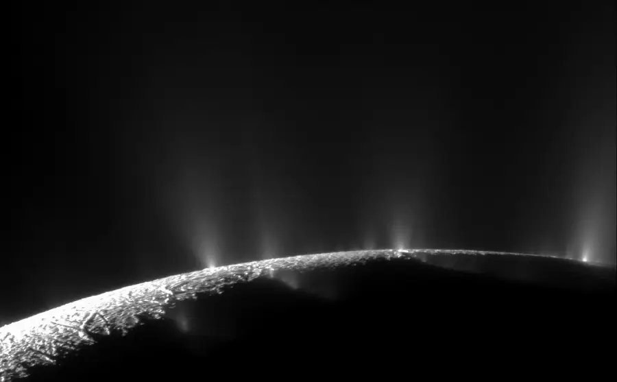 A dark, curved surface with bright, icy plumes shooting into space against a black background, resembling a moon or planet’s surface viewed from the side.