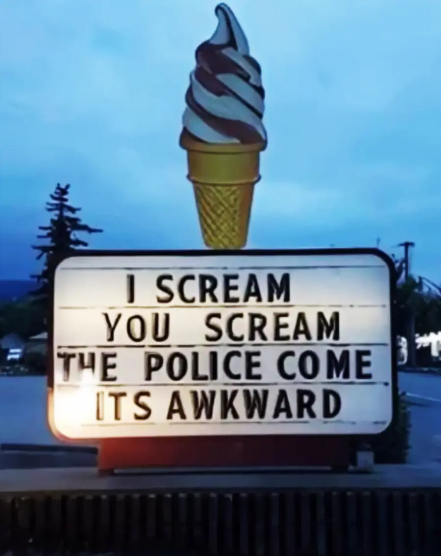 A large ice cream cone sign with a marquee below reads: “I SCREAM, YOU SCREAM, THE POLICE COME, IT’S AWKWARD.” The scene appears to be in a parking lot at dusk.