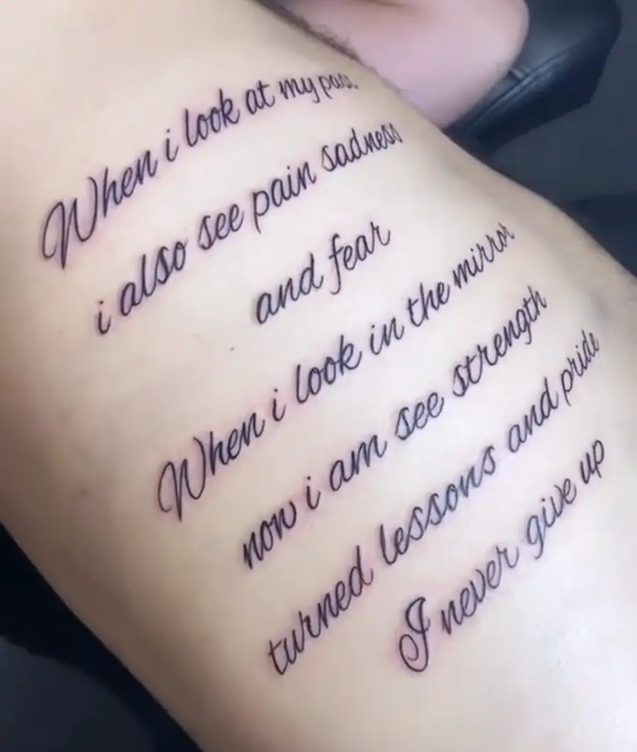 Tattooed script on skin reads: “When I look at my past, I also see pain sadness and fear. When I look in the mirror, now I am see strength, turned lessons and pride. I never give up.”