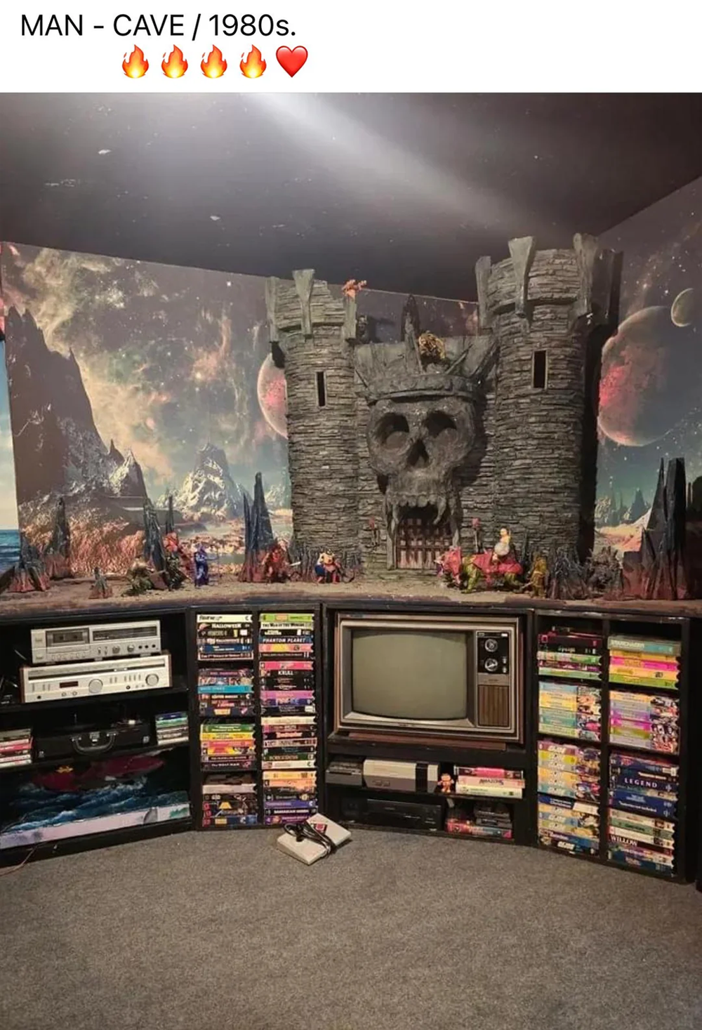 1980s-themed room with a vintage TV, shelves full of VHS tapes, action figures, and a large castle playset with a skull entrance, set against a space-themed wall mural.