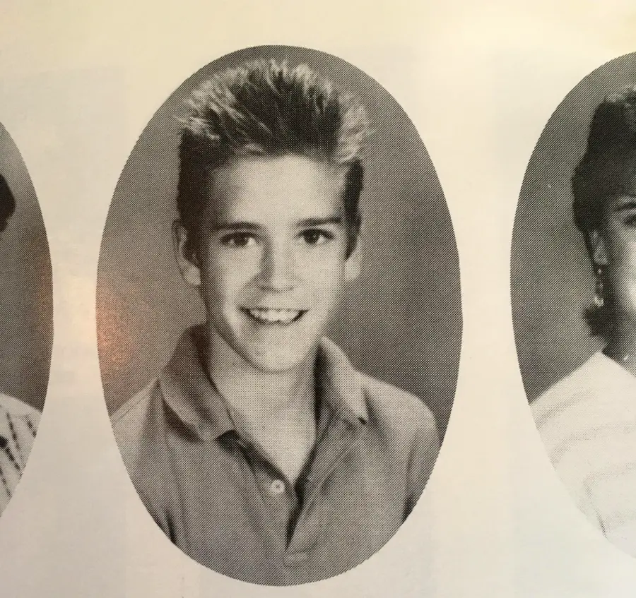 Black and white yearbook photo of a smiling young boy with short, spiky hair, wearing a collared shirt, shown from the chest up in an oval frame.