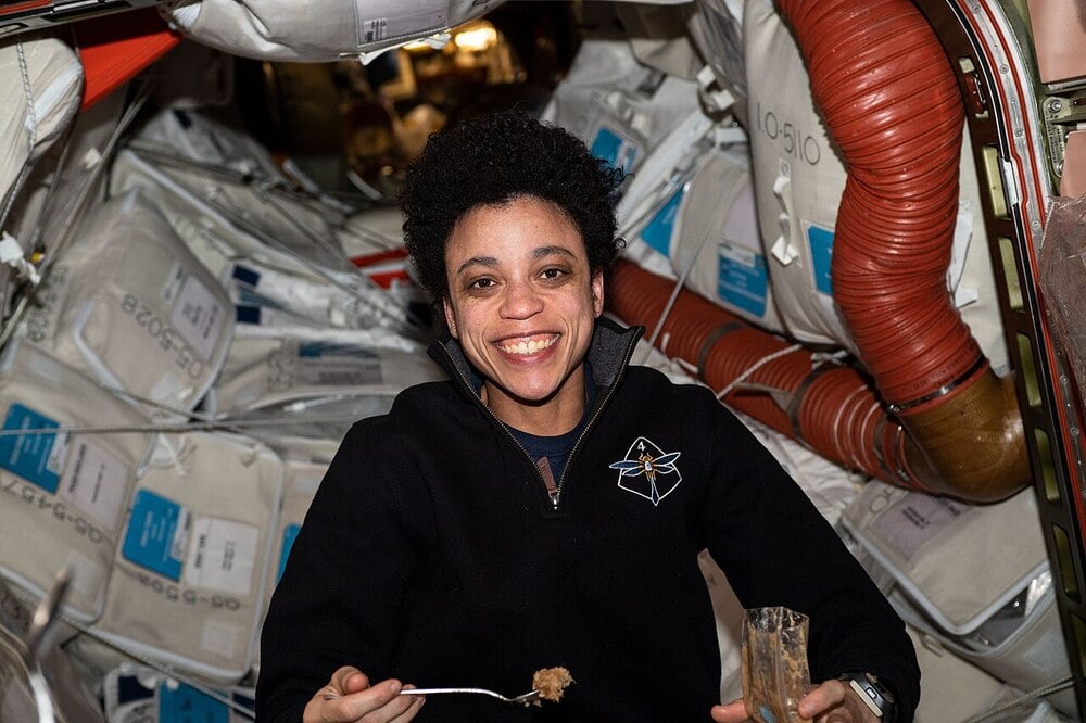 An astronaut eats with a fork inside the International Space Station.