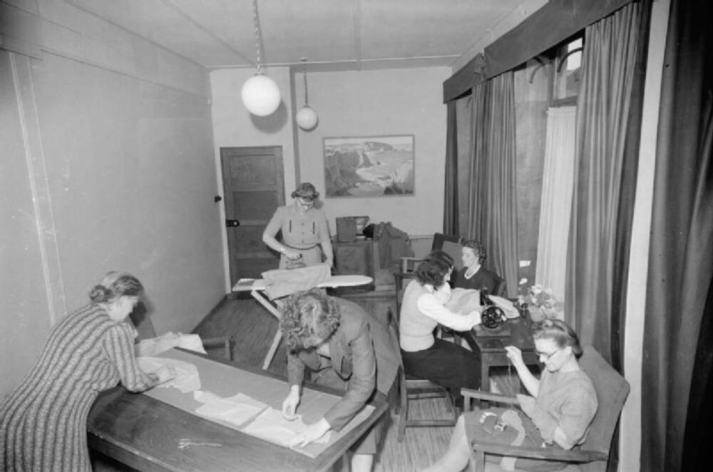 People sewing and repairing fabric at tables.