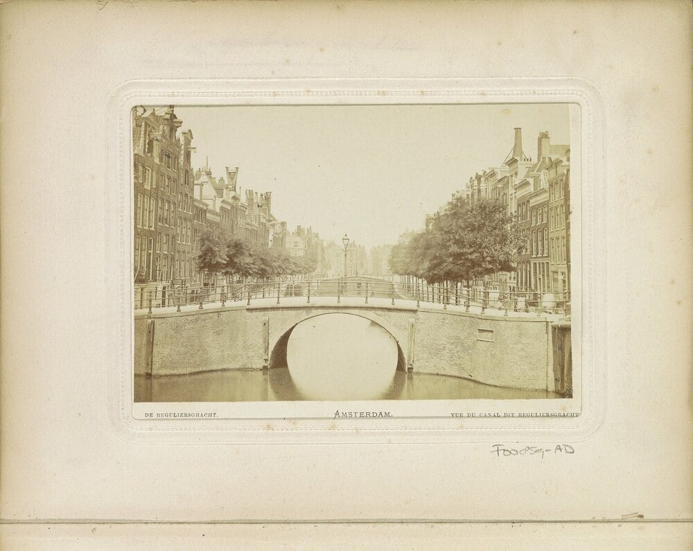 Historic view of an arched bridge spanning a canal in Amsterdam.
