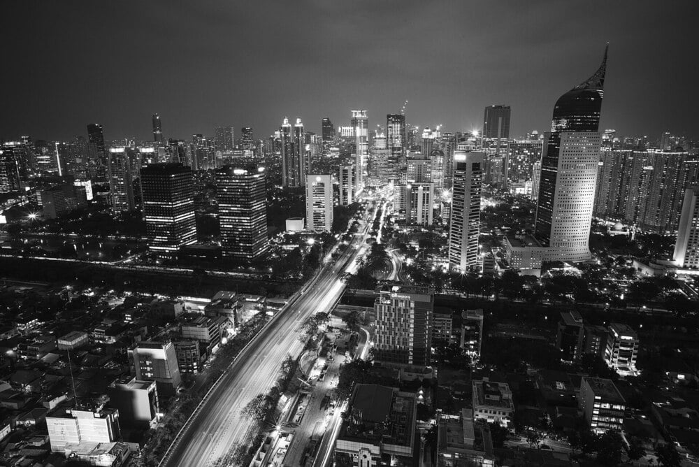 Aerial night view of Jakarta with skyscrapers and illuminated roads.