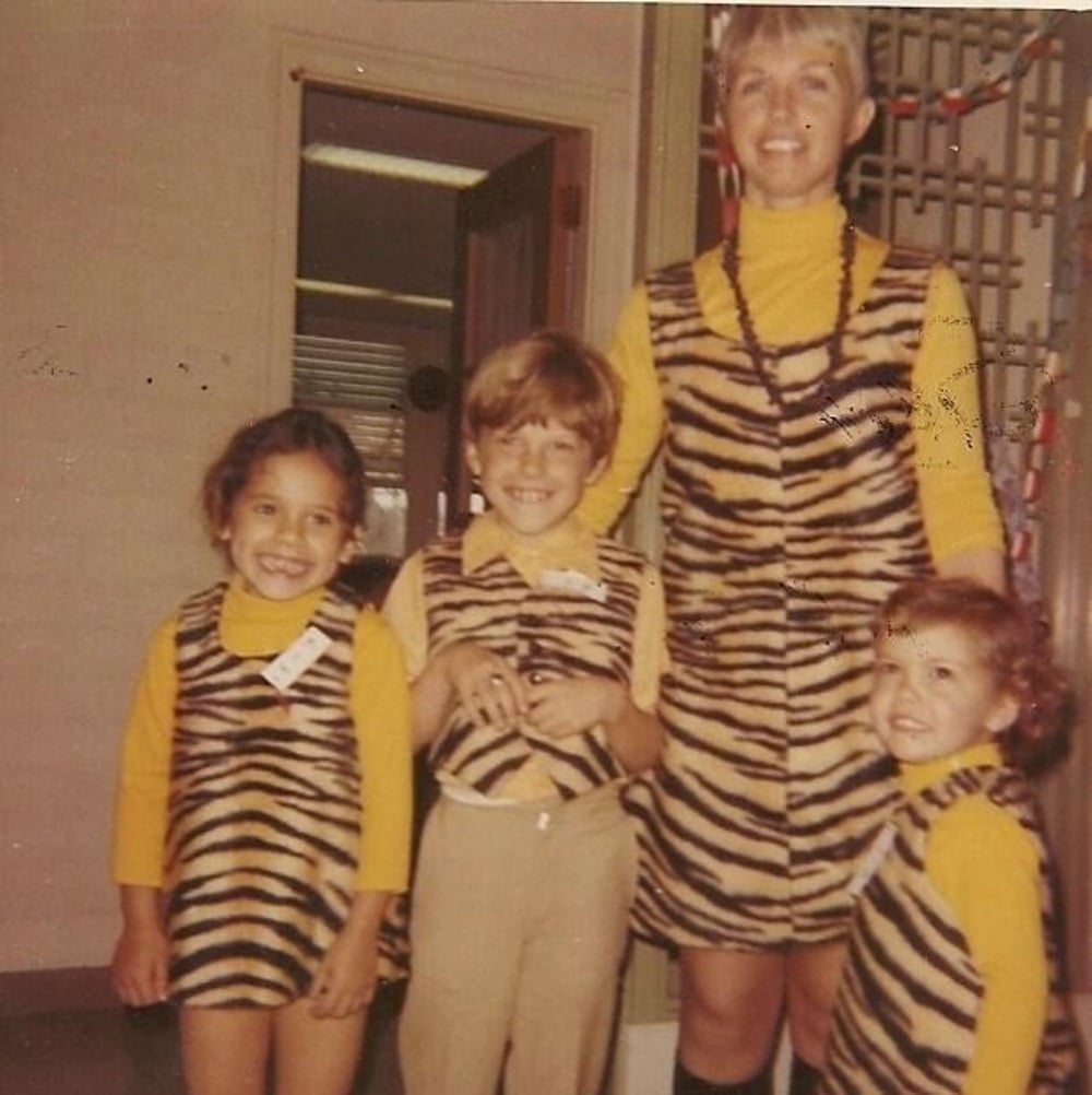 Three children and an adult wear matching tiger-striped outfits.