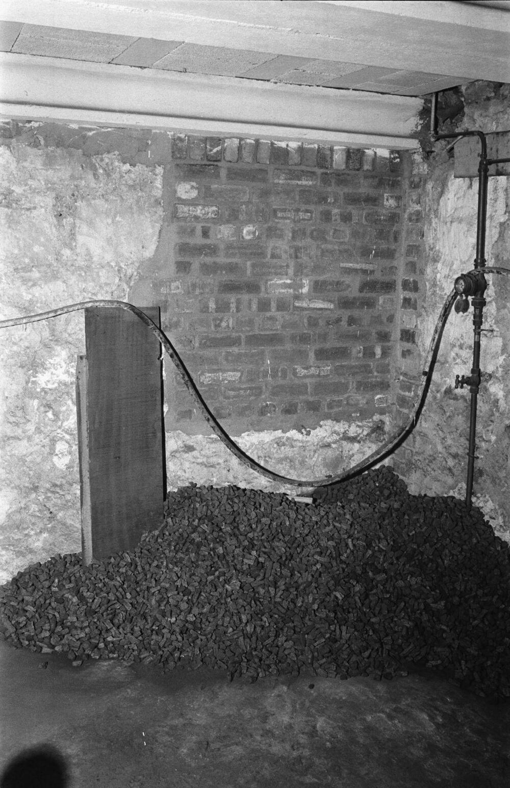 A pile of coal stored in a brick and stone cellar.