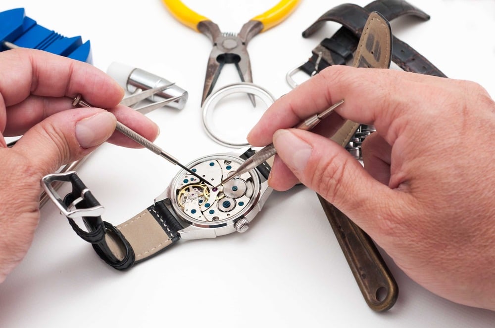 A person repairing the internal mechanism of a wristwatch.