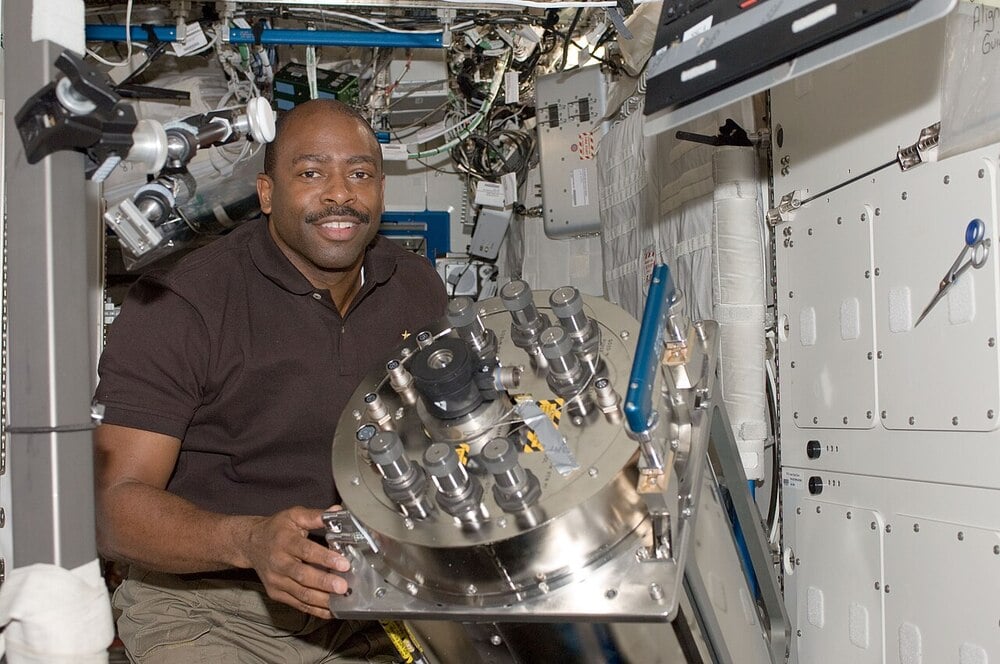 An astronaut works with urine-processing equipment inside a space station.