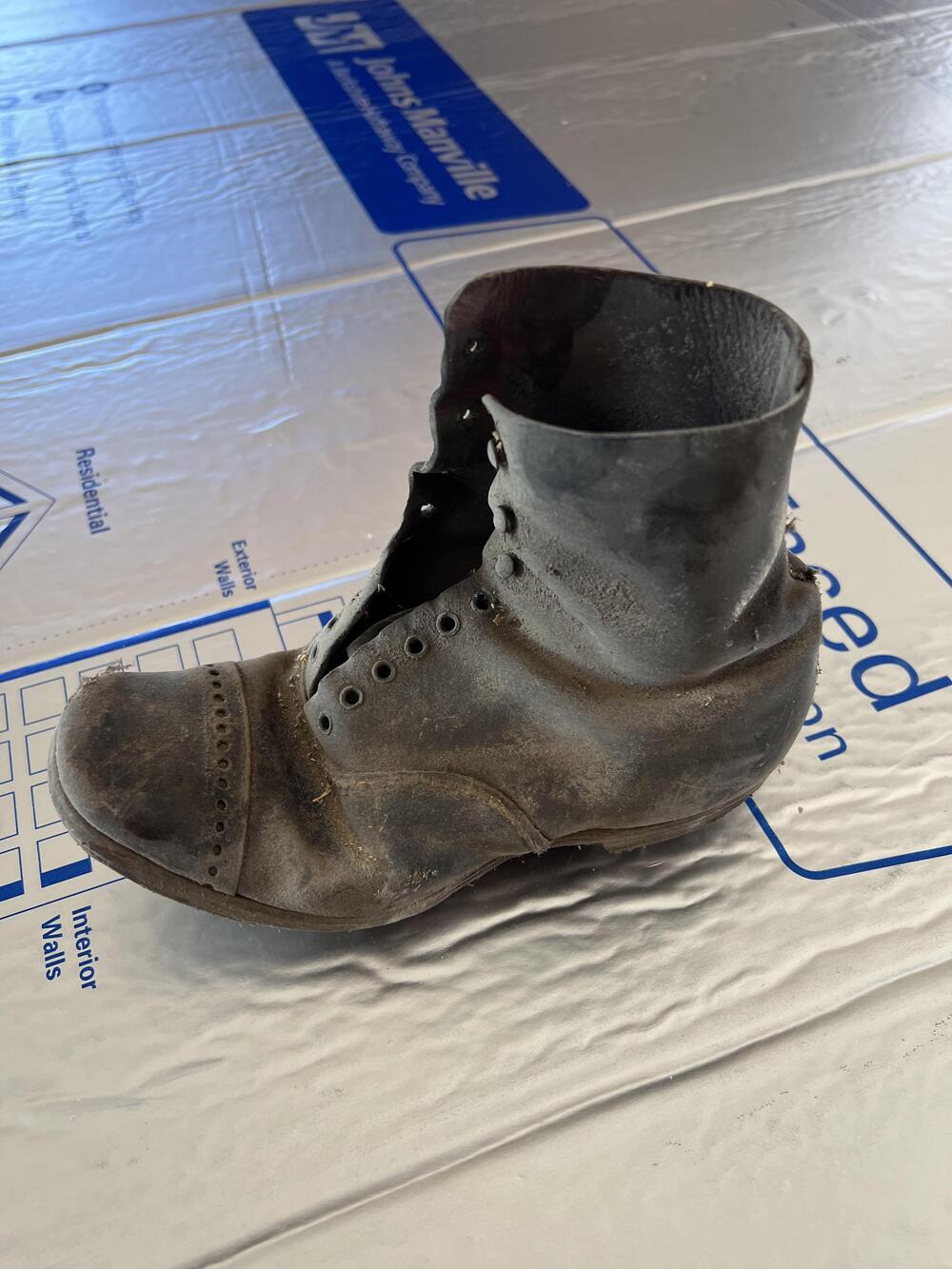 A worn dusty brown leather boot found during renovation.