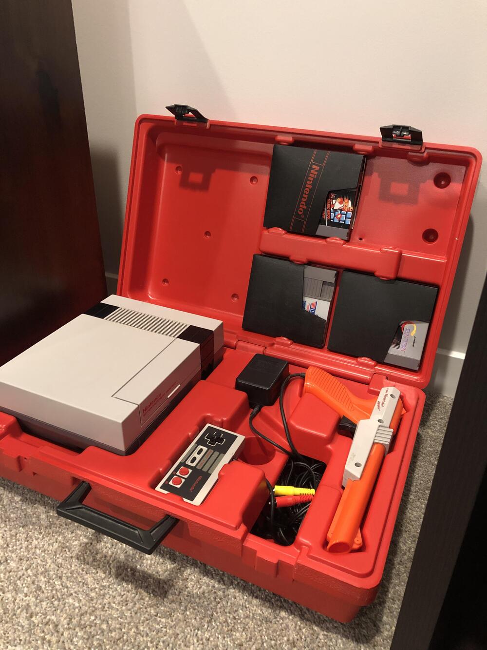 An NES console and games inside a red rental carrying case.
