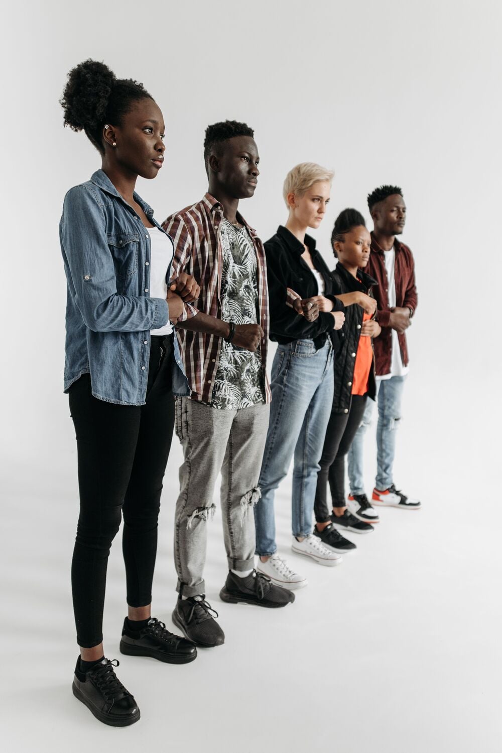 Five people stand side by side in a row, facing left, against a plain white background.