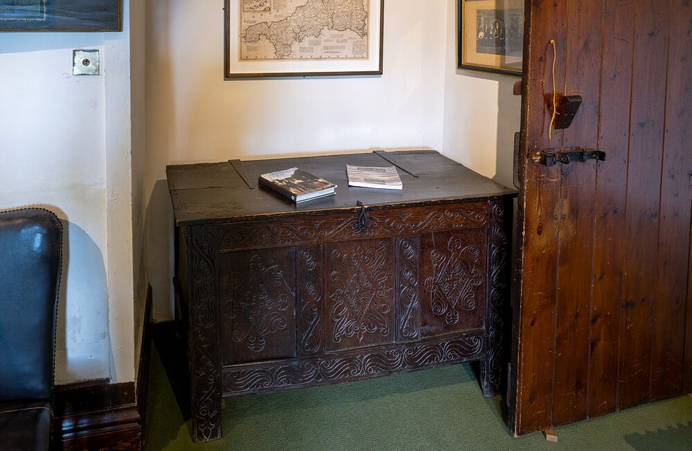 A historic breakfast room interior with carved wooden furniture and framed artwork.