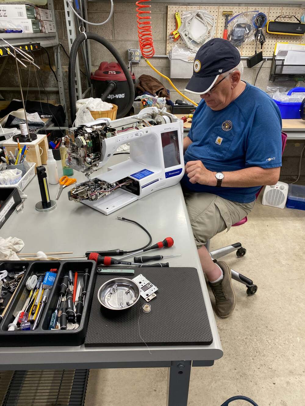 A person repairing a sewing machine in a workshop.