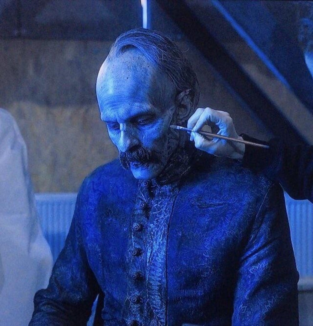 Behind-the-scenes makeup is applied to an actor.