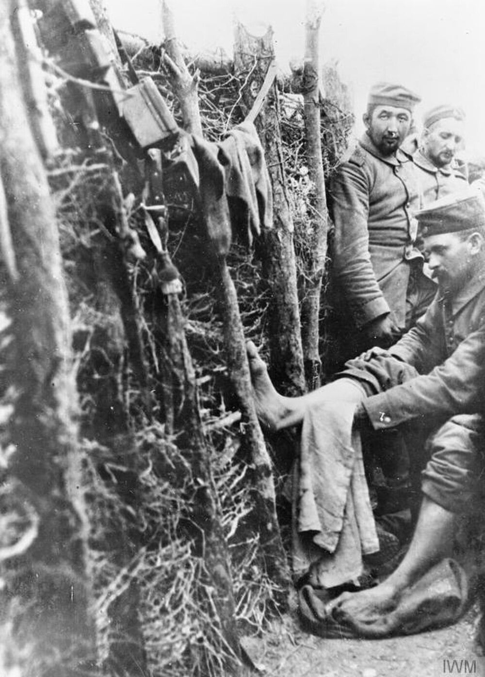 World War I soldiers caring for feet in a trench