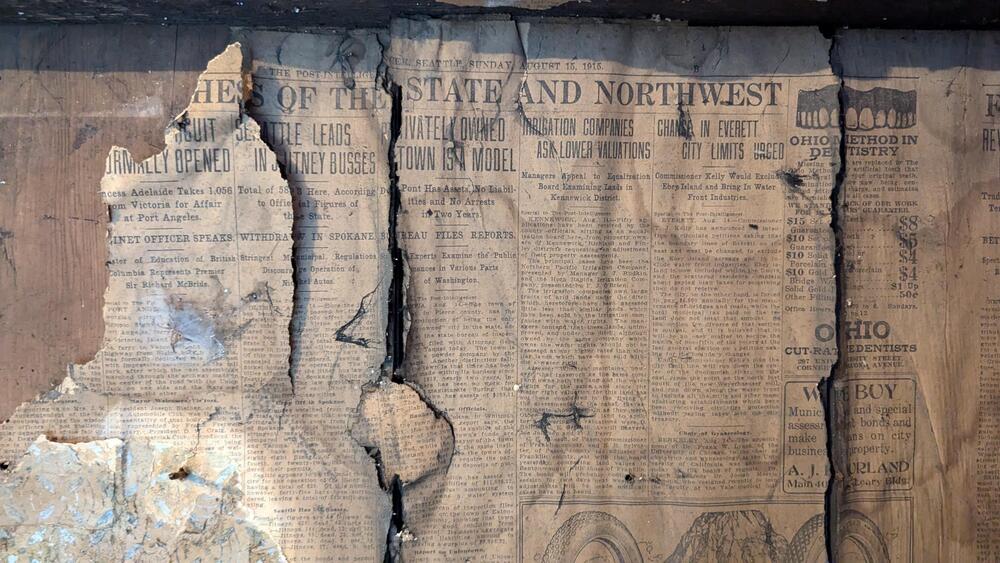 Weathered old newspaper exposed within a wall.