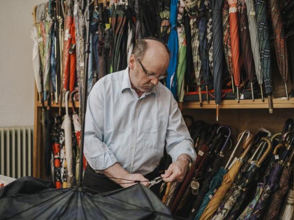 A person repairing an umbrella in a repair shop.
