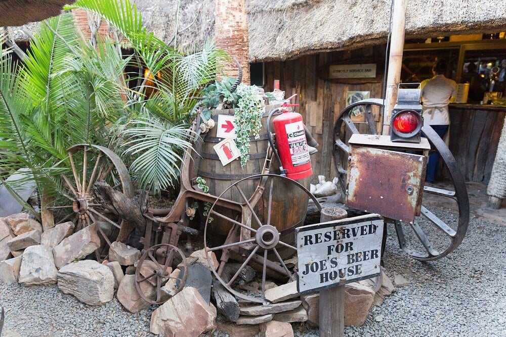 A rustic display outside Joe's Beer House with barrels, wagon wheels, and a reserved sign.