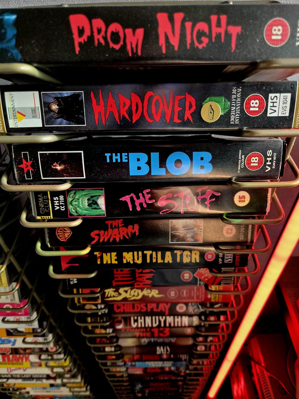 A rack of horror VHS tapes with bold title lettering.