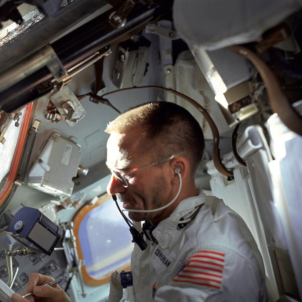 An astronaut writes with a space pen inside a spacecraft.