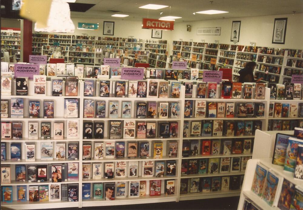 Rows of VHS boxes on display inside a video rental store.