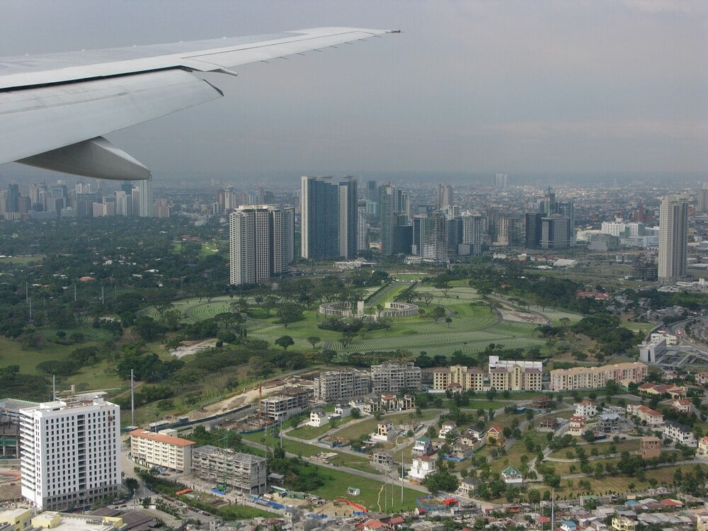 Aerial view of Manila with skyscrapers, parks, and residential areas.