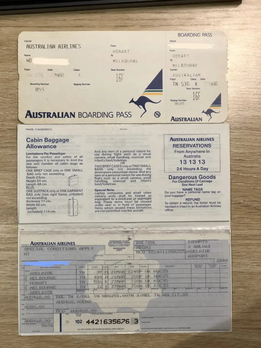 An Australian Airlines boarding pass and flight ticket from Hobart to Melbourne, placed on a wooden surface. The ticket shows seat 16F and includes baggage and reservation information.