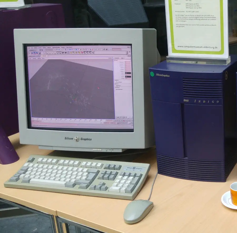 A vintage Silicon Graphics Indigo computer with a CRT monitor displaying 3D modeling software sits on a desk alongside a keyboard and mouse.