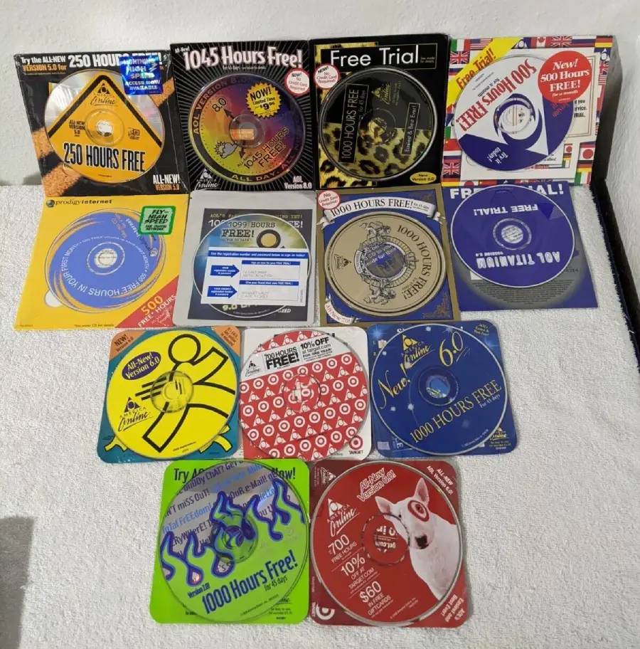 A collection of old AOL and internet service provider CDs arranged in a grid on a white surface, each advertising free internet hours or trial offers.