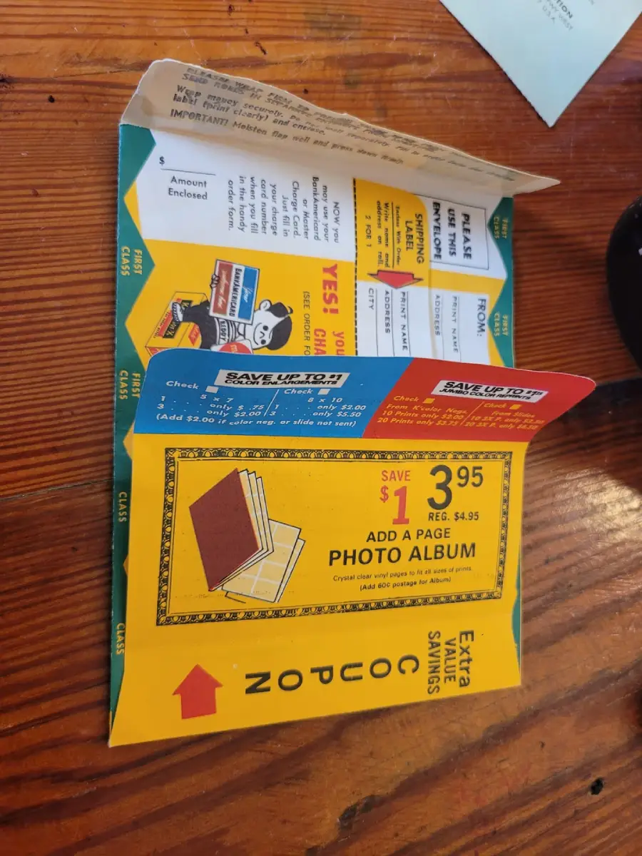 An open vintage mail-in order form and coupon booklet sits on a wooden table, showing offers for a $3.95 photo album and sections to fill out personal information for ordering.