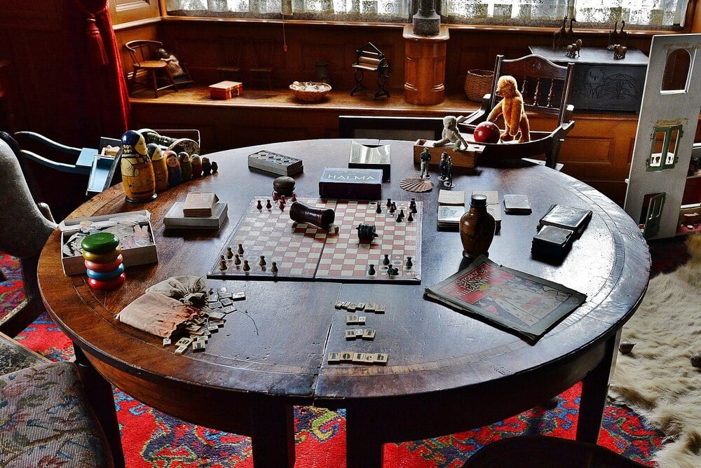 A historic day nursery with a table, toys, books, and wooden furniture.