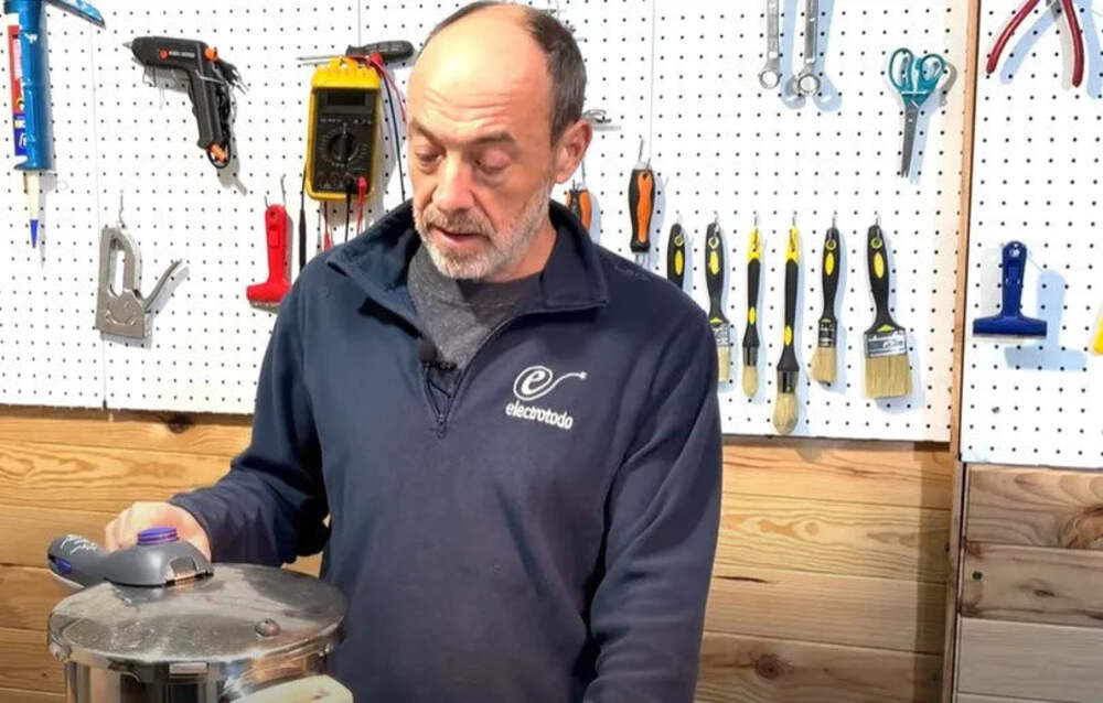 A person holding a pressure cooker in a workshop.