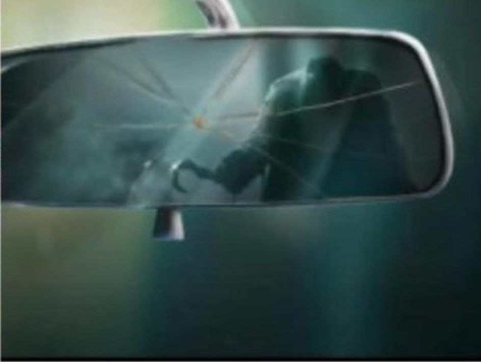 A cracked car rearview mirror shows the reflection of a person outside holding a crowbar, suggesting a possible break-in or theft attempt.