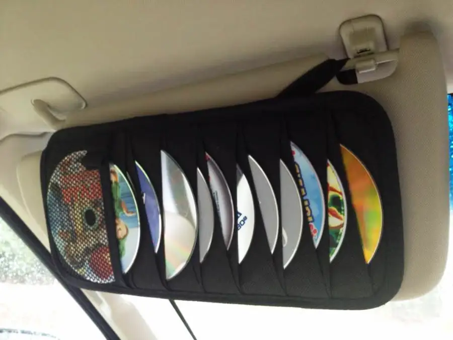 A car sun visor holds a black CD organizer with several CDs partially visible in its slots.