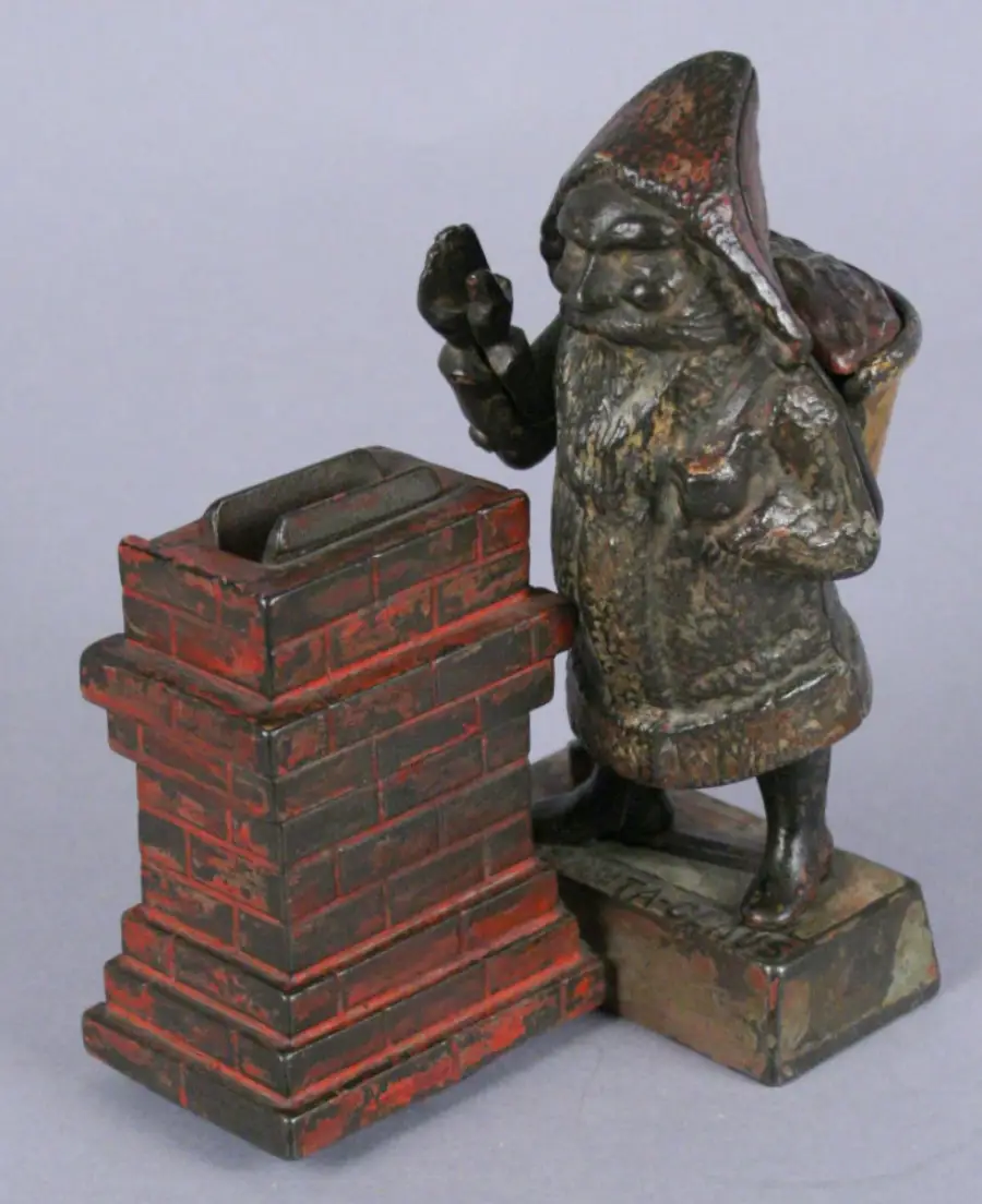 Antique cast-iron mechanical coin bank featuring Santa Claus standing next to a red brick chimney. Santa holds a pipe, carries a sack on his back, and raises one hand. The base is marked “SANTA CLAUS.” The paint is worn from age.