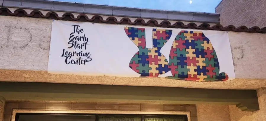 A sign reads “The Early Start Learning Center” next to two bunny shapes filled with colorful jigsaw puzzle patterns, hanging on a building exterior.
