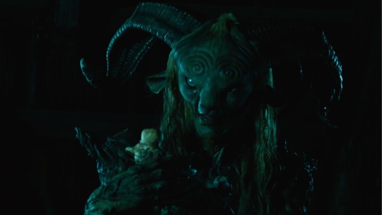 A mystical creature with ram-like horns and mossy skin holds a small, pale figurine in its clawed hand, set against a dark background.