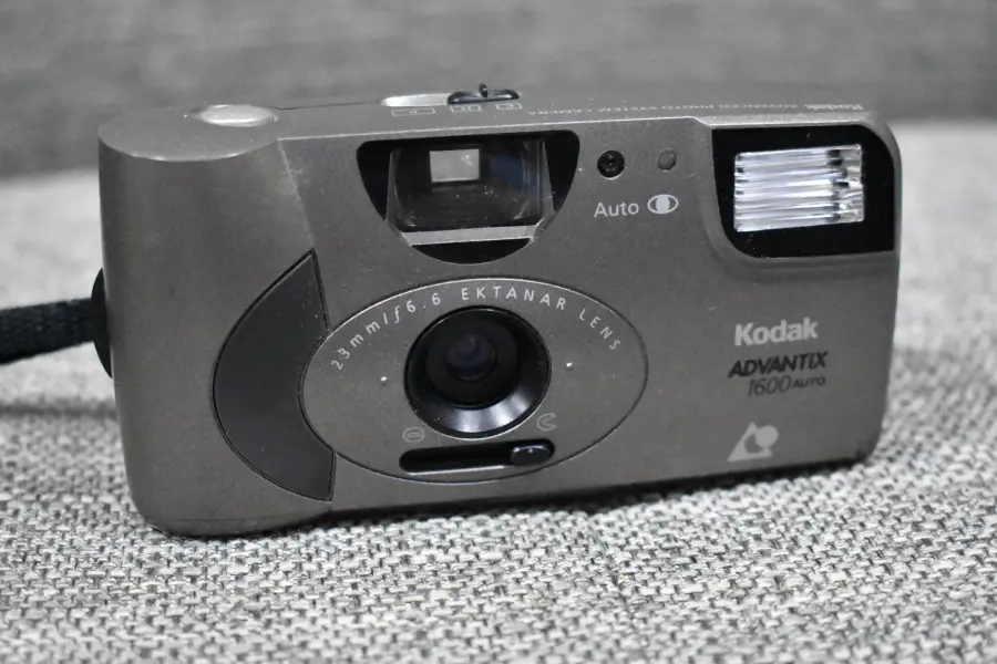 A close-up of a Kodak Advantix 1600 Auto film camera resting on a gray fabric surface. The camera lens, flash, and brand name are clearly visible.